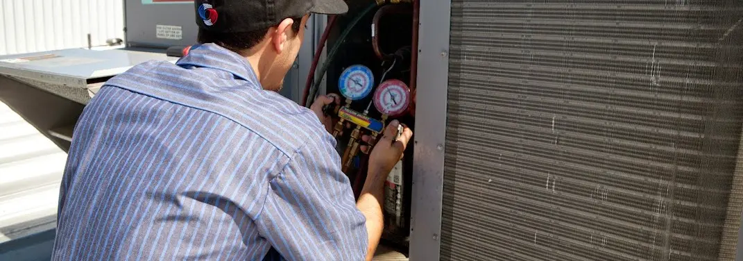 HVAC technician servicing a condenser unit in Greenville